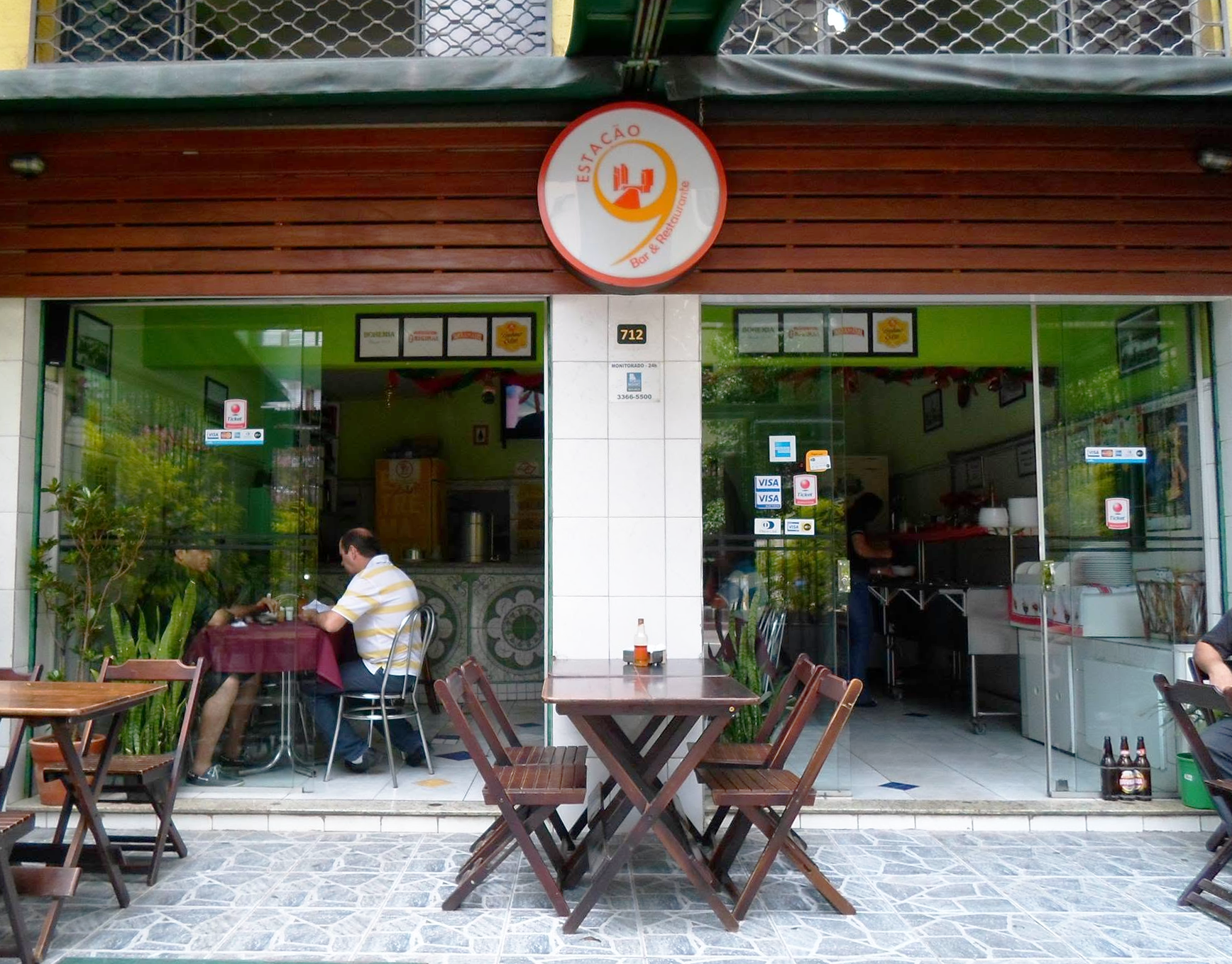 Fachada do Estação Nove Bar e Restaurante, com mesas na calçada e o letreiro redondo característico